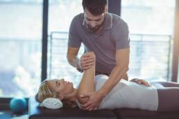 Physiotherapist giving shoulder therapy to a woman