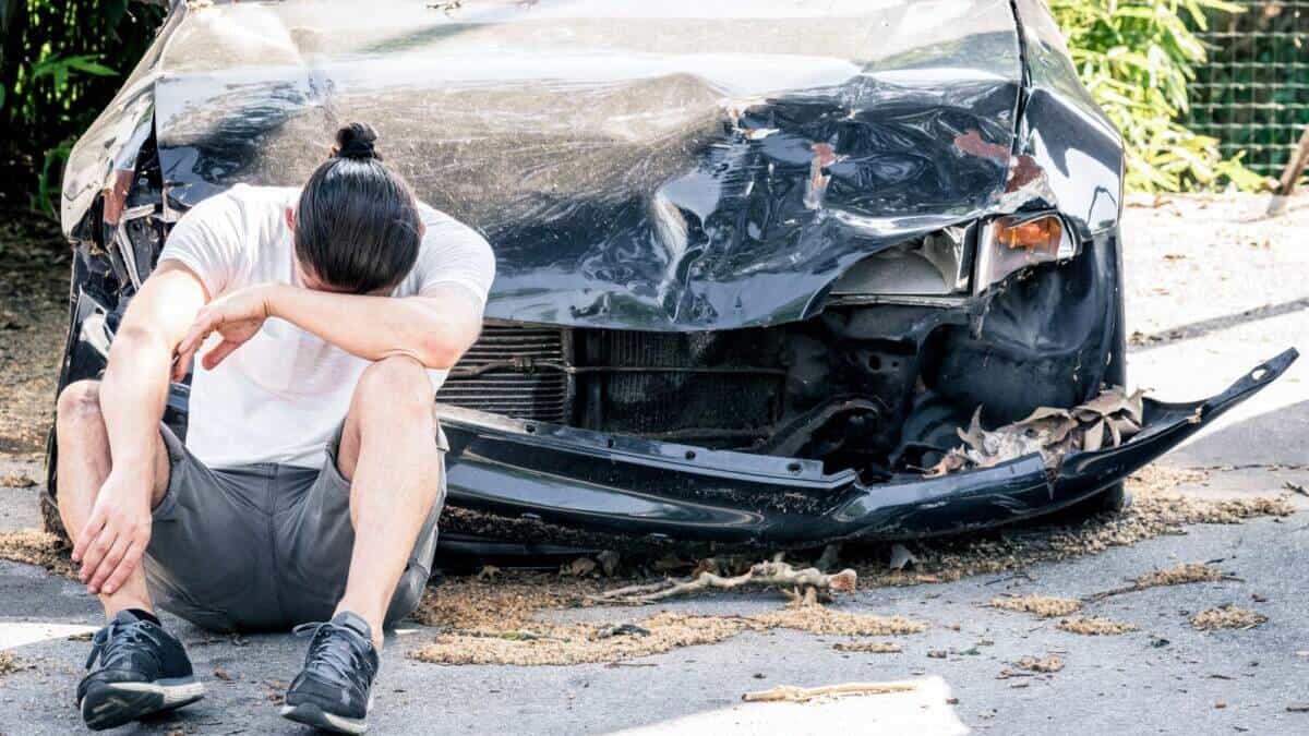 Man crying on his old damaged car after crash accident
