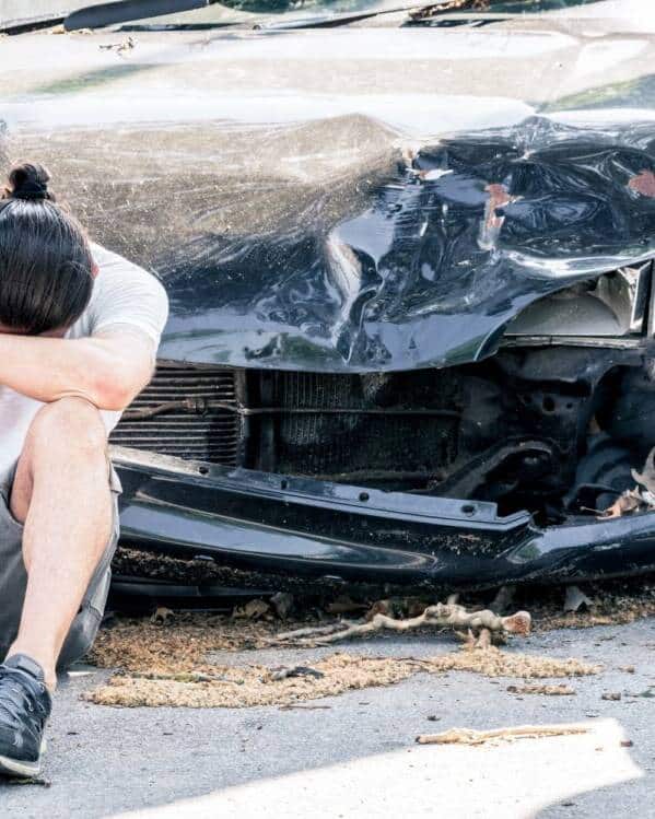 Man crying on his old damaged car after crash accident