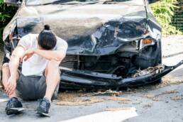 Man crying on his old damaged car after crash accident