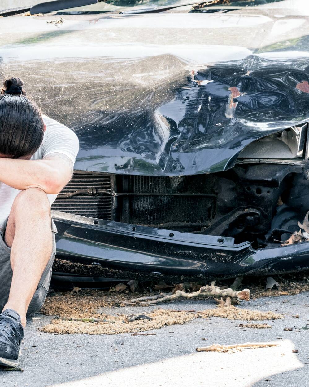 Man crying on his old damaged car after crash accident