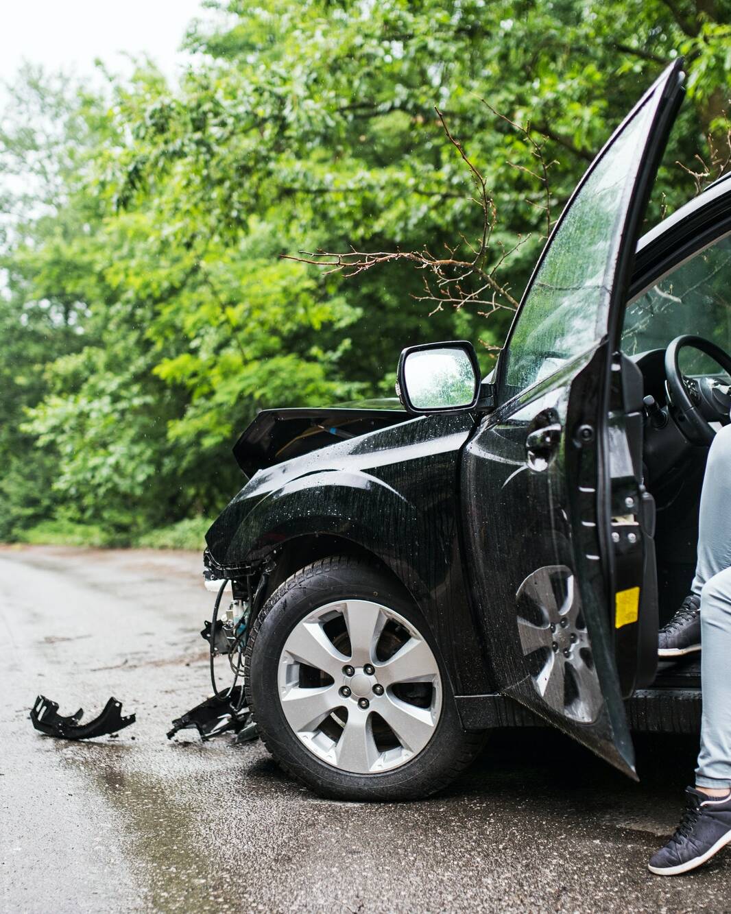 Young woman in the damaged car after a car accident, making a phone call.